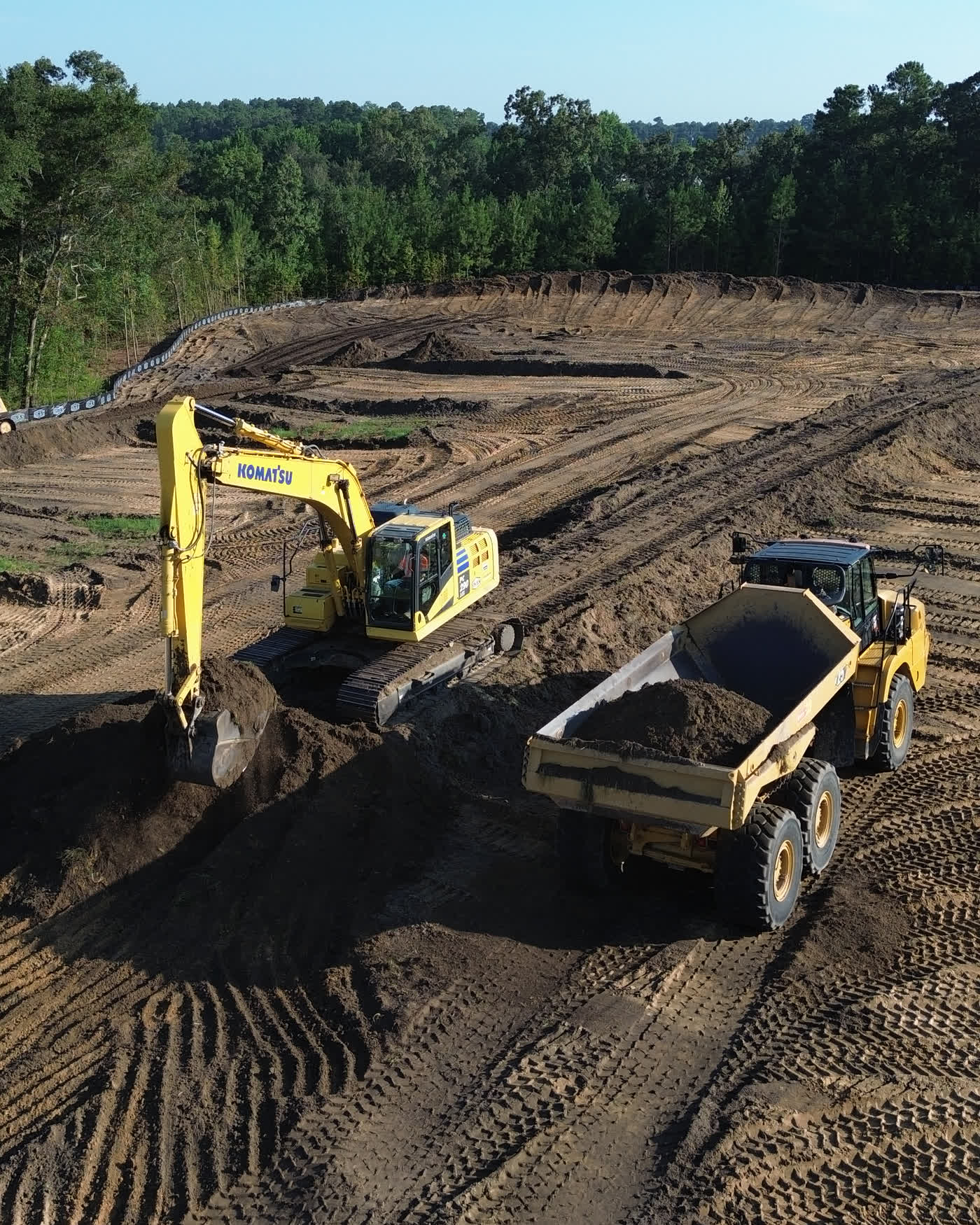 A Komatsu excavator loading an articulated dump truck during site grading at the Homestead development